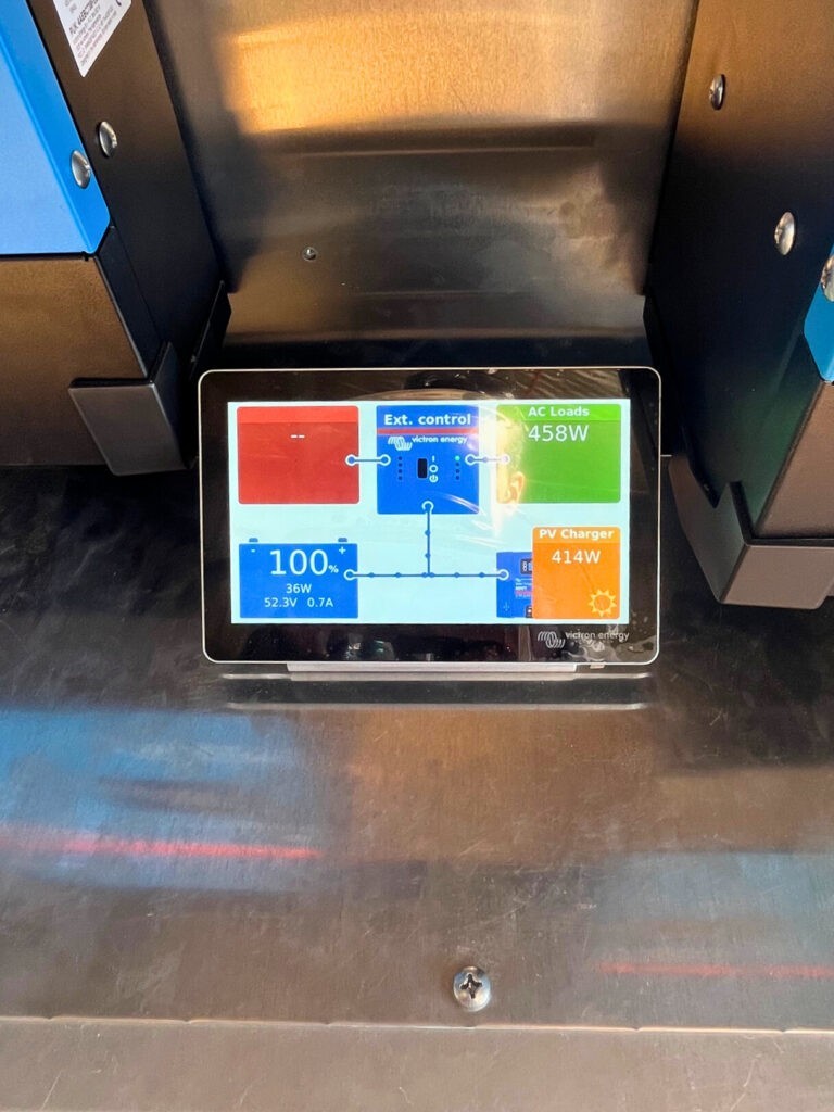 Victron Energy solar power monitor display showing battery status and energy consumption metrics.